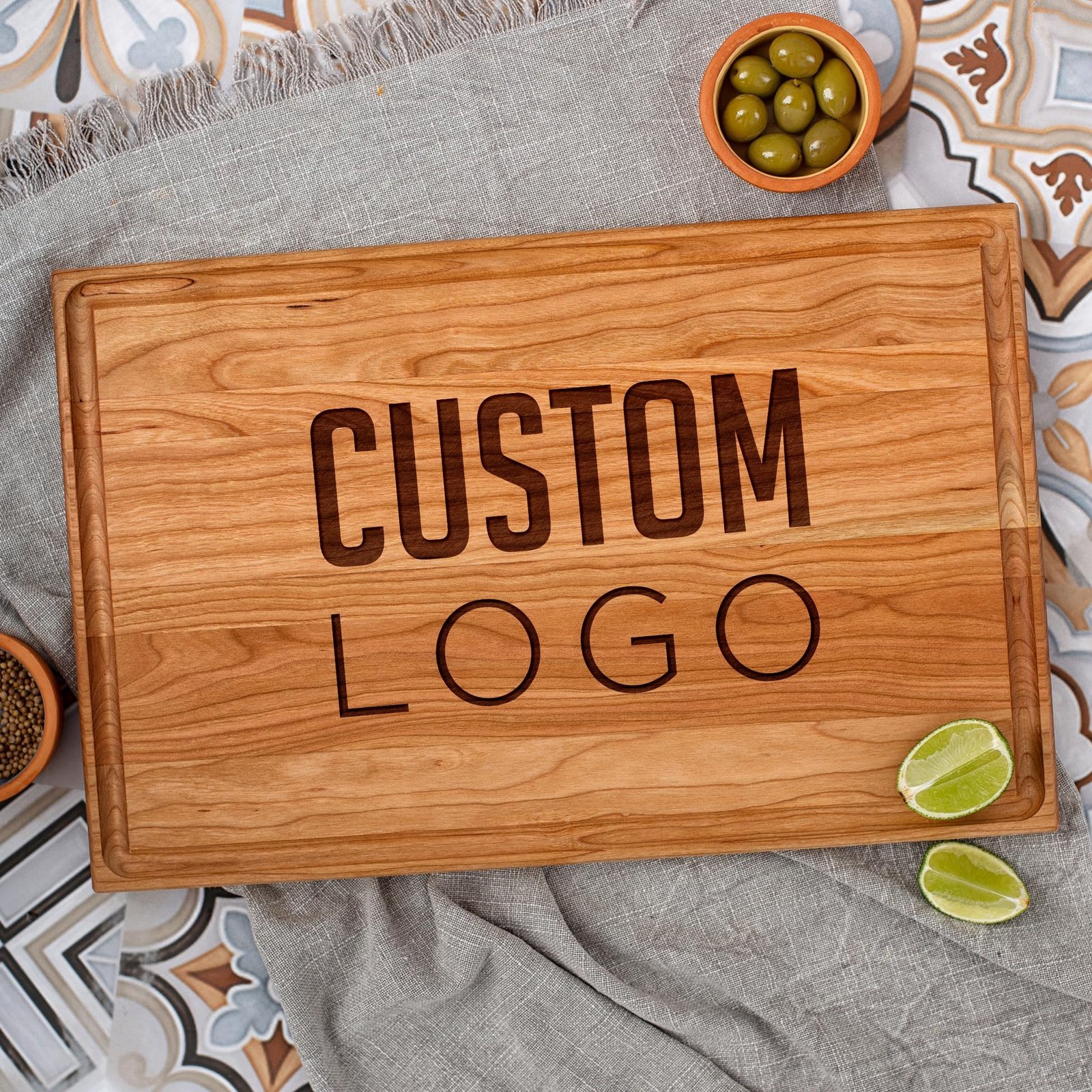 Wooden cutting board with "CUSTOM LOGO" engraved, olives, and limes